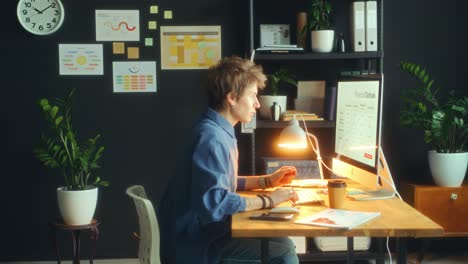 young woman entering office and working on computer at desk