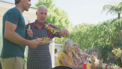 Happy-caucasian-family-having-barbecue-and-eating-in-garden