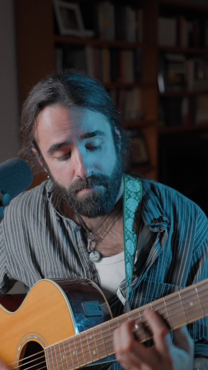 Man playing acoustic guitar under blue light