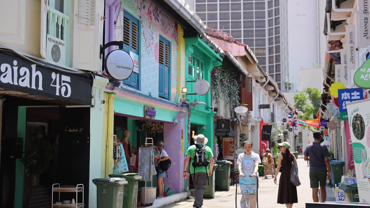 People walking along vibrant, colorful street with murals and shops on a sunny day
