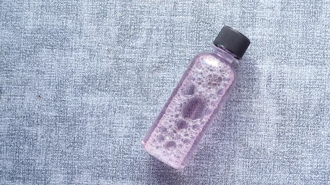 botella de líquido de espuma rosada en tela gris