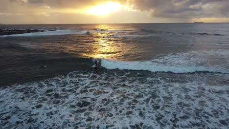 Aerial-drone-shot-of-morning-mal-surfer-riding-ocean-wave-with-beautiful-sun-rise-reflection-travel-tourism-Pacific-Ocean-NSW-Central-Coast-Australia-4K