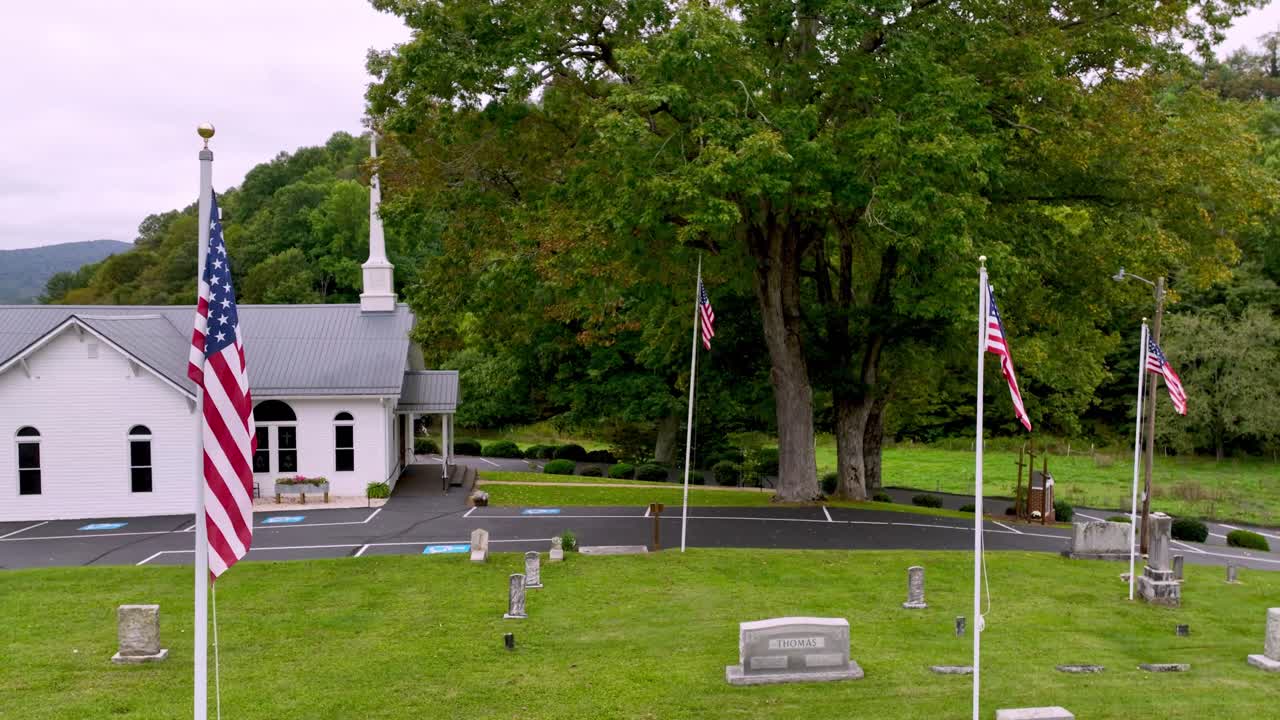 cementerio con banderas americanas y iglesia bautista en el fondo aérea en zionville nc, carolina del norte cerca de boone nc, carlina del norte