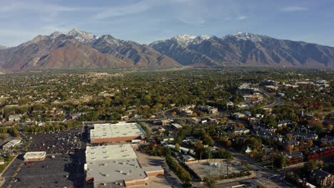 Kippen-Sie-Die-Luft-Nach-Rechts,-Um-Eine-Weite-Landschaftsaufnahme-Der-Atemberaubenden-Schneebedeckten-Rocky-Mountains-Von-Utah-Mit-Dem-Salt-Lake-County-Voller-Gebäude-Und-Farbenfroher-Bäume-An-Einem-Warmen,-Sonnigen-Herbsttag-Zu-Machen