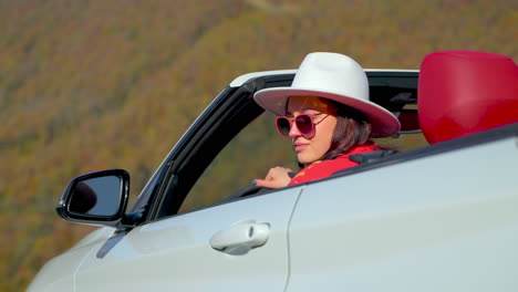 mujer conduciendo un descapotable a través de la escénica follaje de otoño