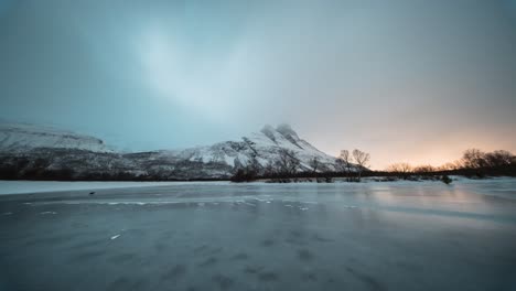 snowy otertinden mountain at sunrise with a frozen lake, creating a serene winter scene