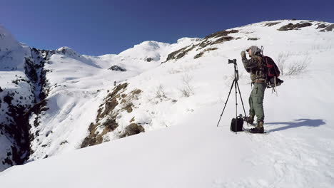 un fotógrafo de naturaleza y vida silvestre se prepara para capturar una foto de un paisaje invernal en las montañas cubiertas de nieve de la isla de kodiak, alaska