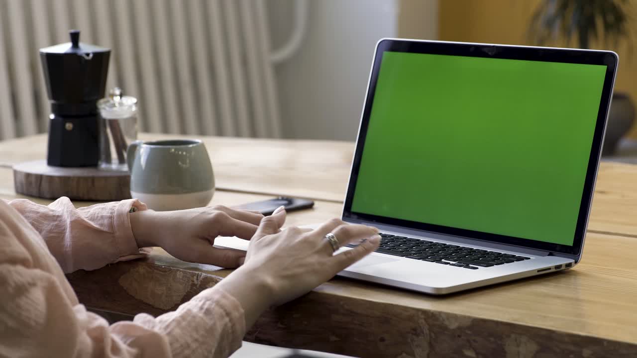 mujer trabajando en una computadora portátil con una pantalla verde en casa