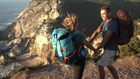 una pareja de mochileros emocionados de pie en un acantilado