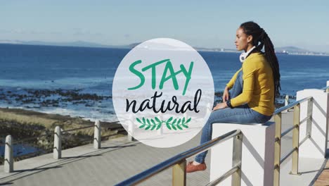 stay natural text banner against african american woman wearing headphones on the promenade