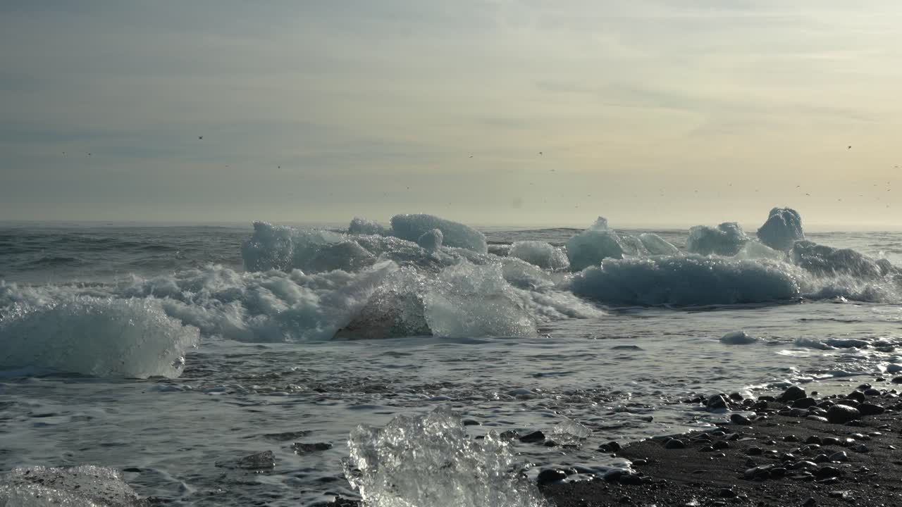 Waves Crashing On Ice Chunks At Diamond Beach With Black Sand In Iceland. wide static shot