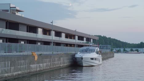 small yacht on a river in front of expensive apartments