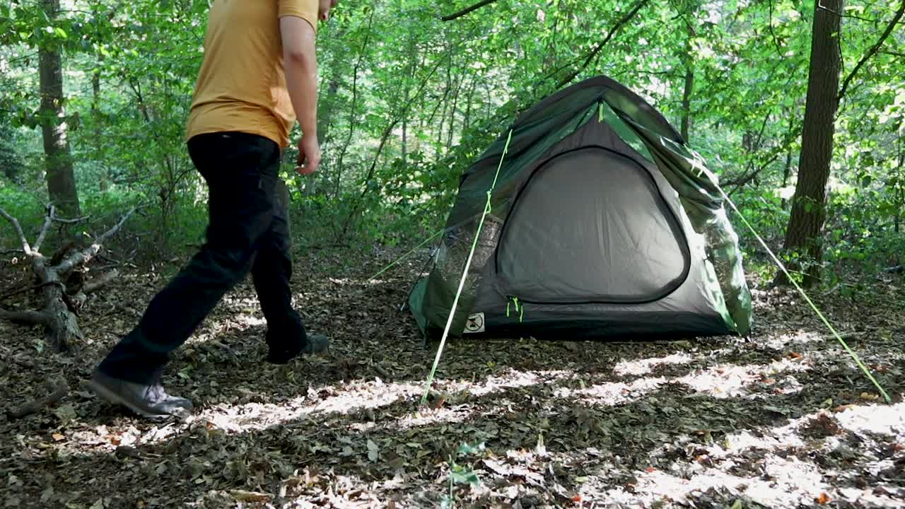 숲 속의 캠프장에서 텐트를 조정하는 관광 남자