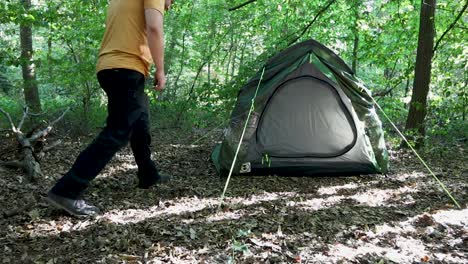 tourist man adjusting the tent at a campsite in the woods