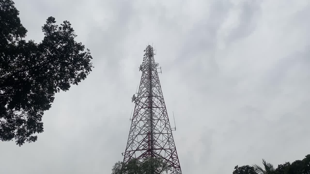 mirando hacia la torre de telecomunicaciones contra las nubes grises