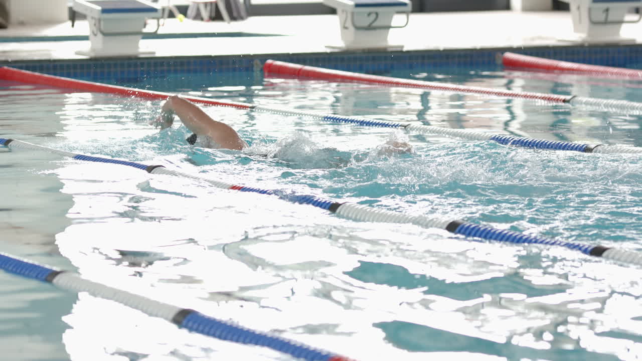 Practicing freestyle stroke, male athlete swimming in pool lane