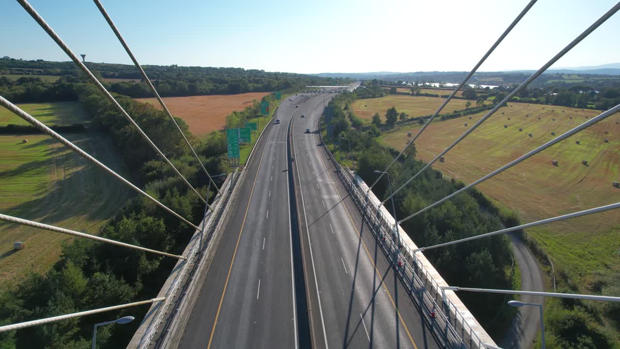 Drone moving out of suspension bridge traffic on dual carriageway and tool booth Waterford Ireland summer evening