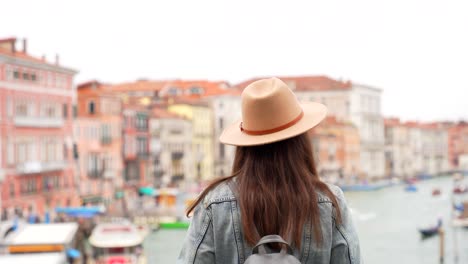 Tourist-woman-with-hat-looking-at-Grand-Canal-from-Ponte-Rialto,-Venezia