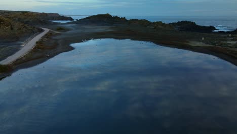 small lagoon in menorca, spain at sunset with reflections of clouds