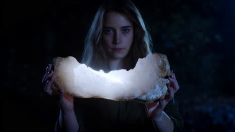 woman holding a glowing crystal geode in the dark
