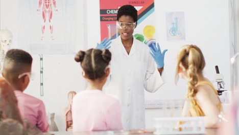 profesora de química afroamericana con estudiantes diversos en el aula, en cámara lenta.