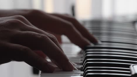 teclado de piano con acercamiento extremo de las manos contra un fondo retroiluminado con color natural y enfoque selectivo