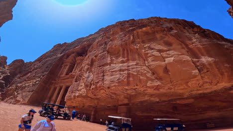 tourists walk along the rock-cut facades. low angle view at the scenery of petra, jordan, west asia.