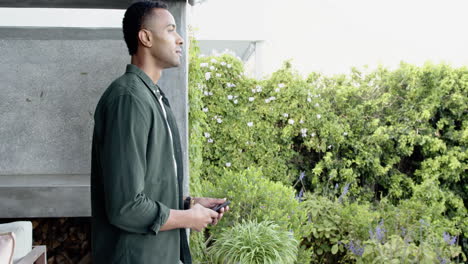 holding smartphone, man standing outside admiring peaceful garden view, copy space