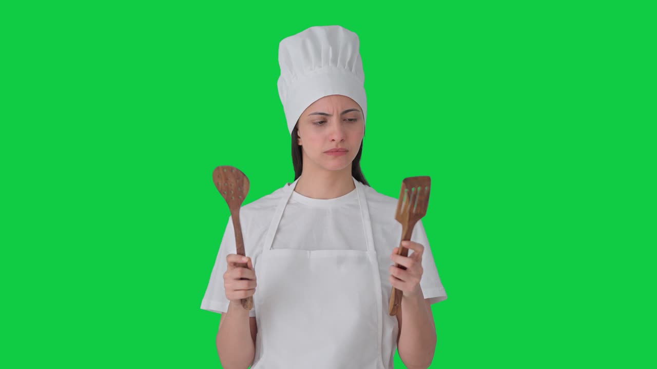 Indian female professional chef posing with spoon and spatula Green screen