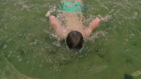 boy with swimming goggles swimming in the lake, happy childhood concept