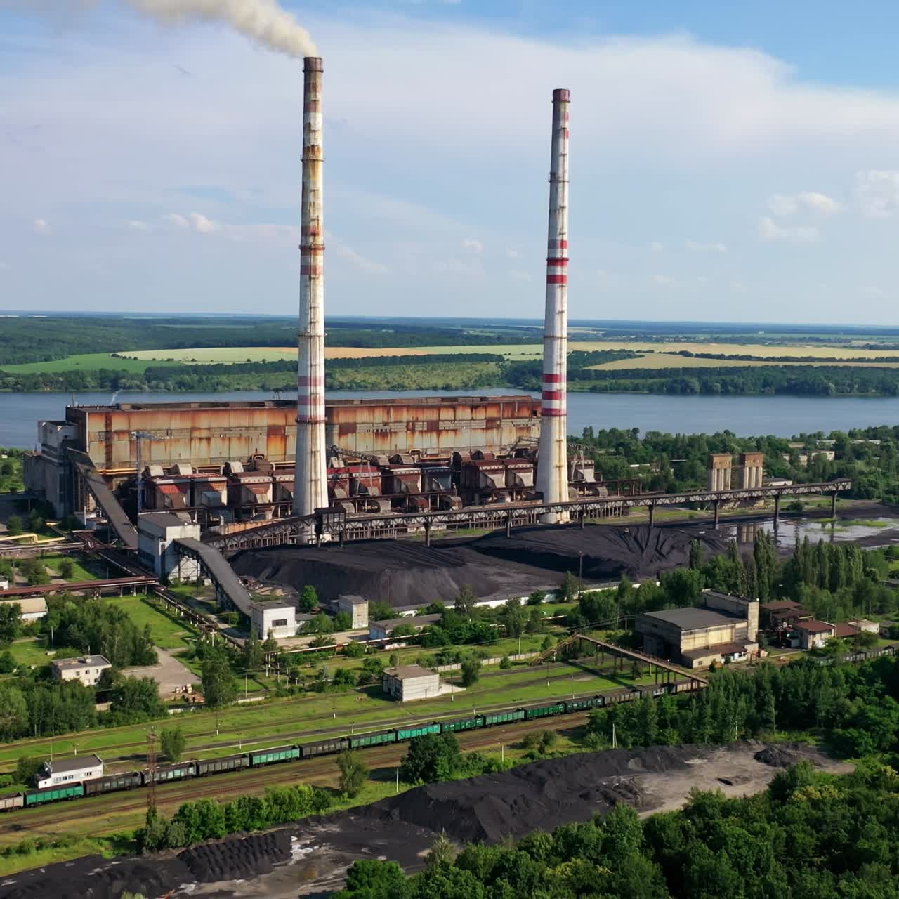 Chemical plant with smoking pipe. Industrial factory among green nature. Pollution of the environment. Aerial view.