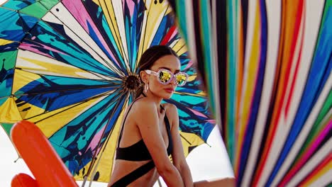 woman in bikini with colorful umbrella on beach