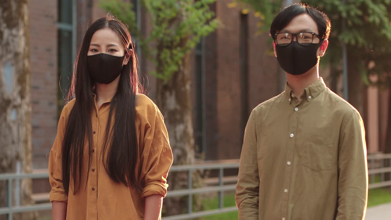 보호용 마스크를 쓰고 거리에서 카메라를 바라보는 아시아 학생들의 허리 위로 초상화는 깔끔한 대학