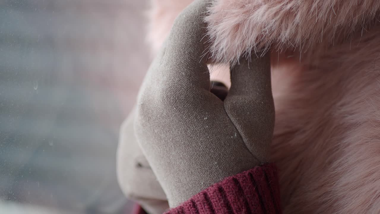 Primo piano di una mano guantata che tocca morbida pelliccia sintetica rosa