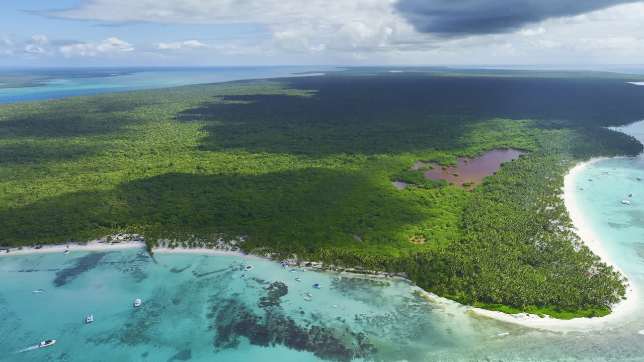 Ripresa aerea con drone leggermente dall'alto sopra una spiaggia nella Repubblica Dominicana, che mostra alcune isole vicine e le aree boschive nell'arcipelago caraibico.