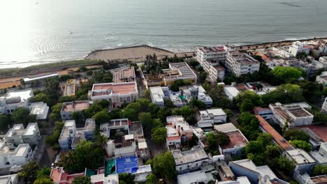 aerial footage of a vibrant coastal town, pondy. the shot features a sandy beach with fishing boats next to a densely packed community of colorful buildings, offering a unique view of seaside living