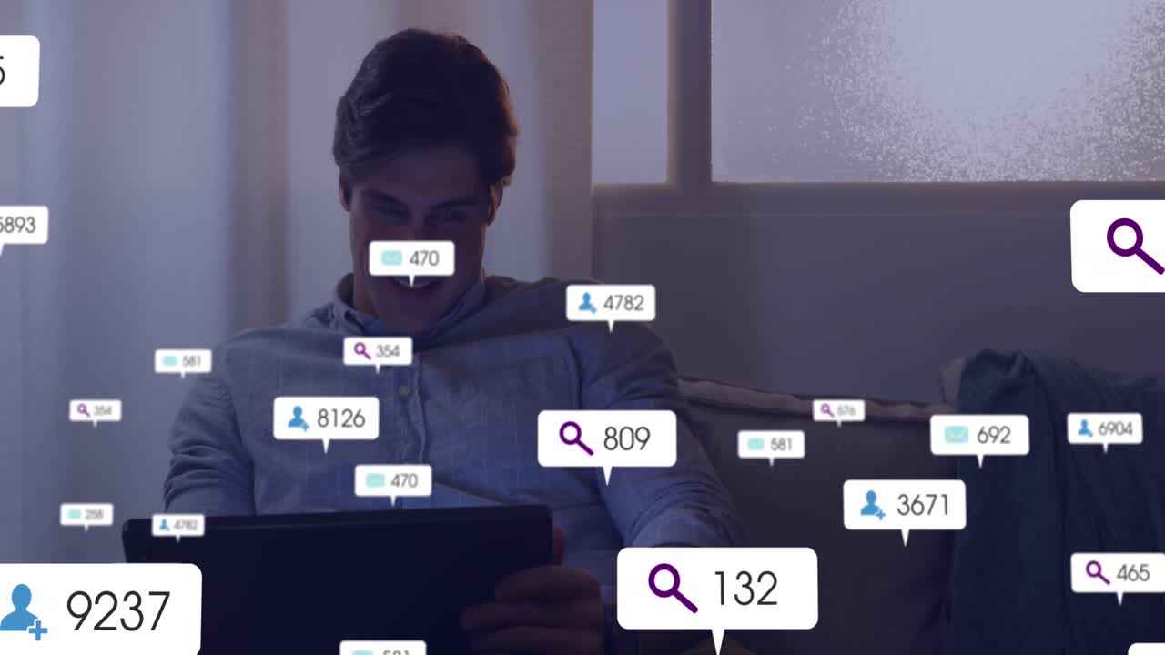 Animation of social media networking icons against happy caucasian man using digital tablet at home