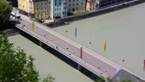 Miniaturszene-Eines-Zeitraffers-Einer-Brücke-über-Einen-Fluss,-über-Die-Busse-Und-Autos-In-Einer-Kleinen-Stadt-Fahren