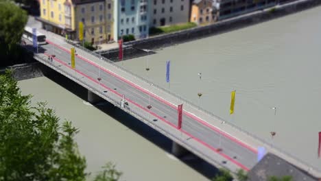 miniature scene of a timelapse of a bridge over a river with buses and cars driving over it in a small city