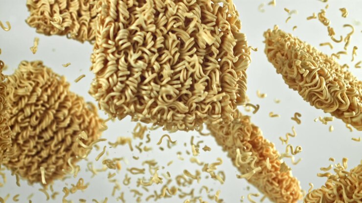 Noodles istantanei secchi che cadono al rallentatore su sfondo bianco