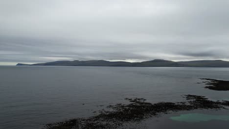 Aerial-drone-view-taking-off-the-rocky-coast-with-algae-of-Kirkjubour,-Faroe-Islands