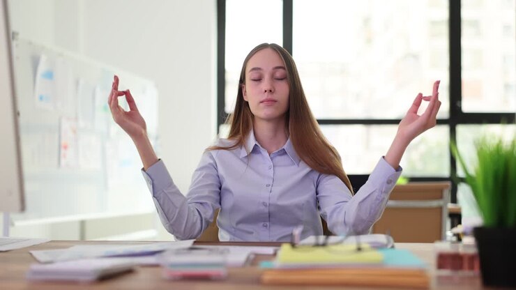 Young woman meditating at her office desk for relaxation and stress relief
