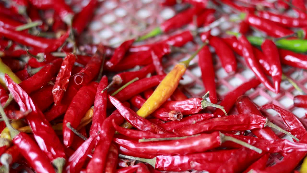 Close-up video of colorful dried red chilies on a woven surface with dynamic camera movement and natural lighting