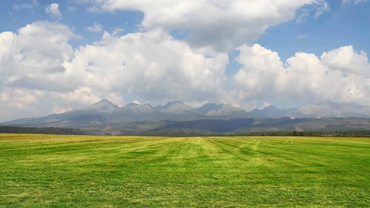 Cloudscape over green field and mountains