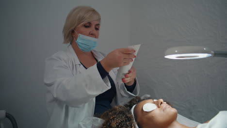 salon cosmetologist holding cream tube. professional preparing for procedure