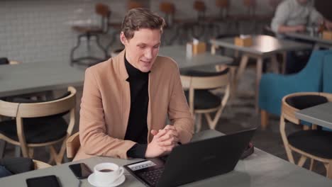 mann redet am laptop im café