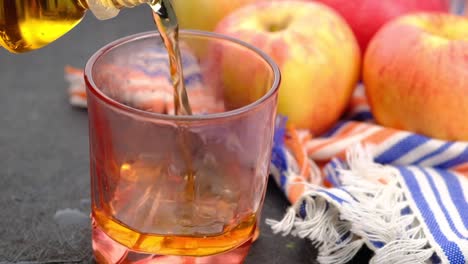 vertiendo sidra de manzana en un vaso con manzanas