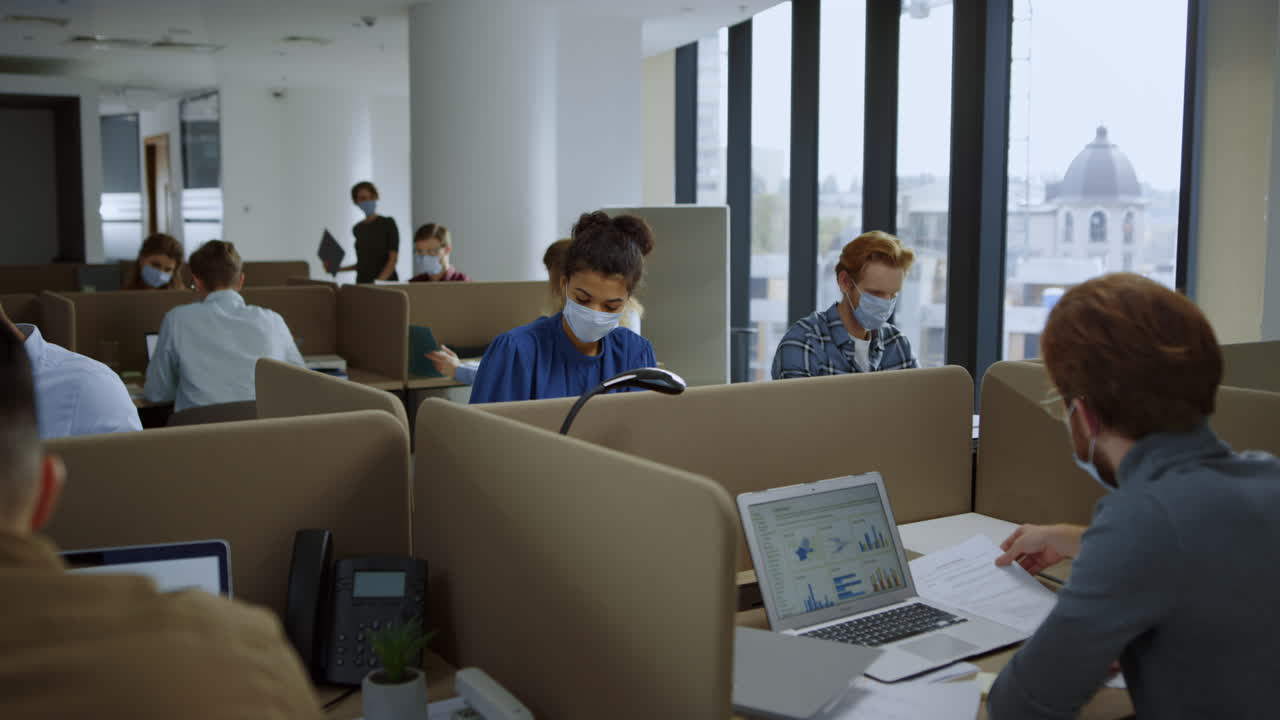 코로나바이러스 전염병 기간 동안 사무실에서 일하는 얼굴 마스크를 입은 사업가들