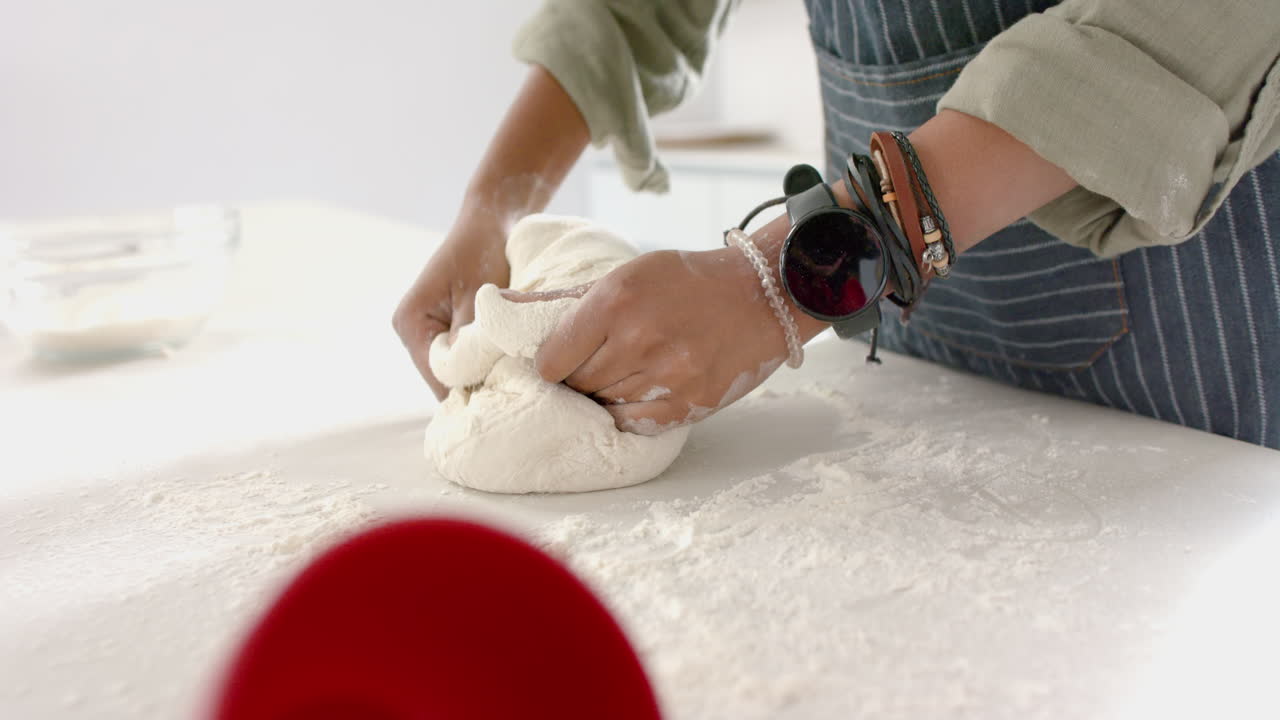 African American young woman kneading dough on kitchen counter
