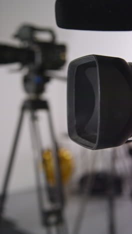 vertical video close up of film camera with lens hood on tripod shooting movie in studio